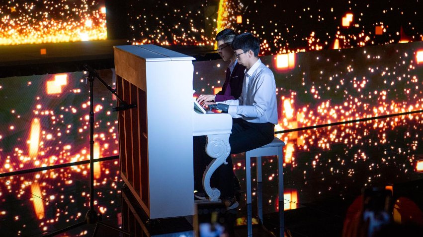 智能仿生手使用者古月與少年鋼琴家舒海峰合奏。主辦方供圖